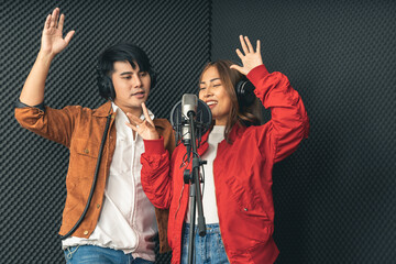 Asian couple singers in a recording studio using a studio microphone with passion in music recording studio