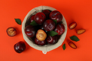 Decorative bowl with plums on an orange background
