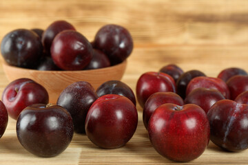 Plums in a wooden bowl on a wooden table