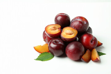 Tasty plums with leaves on white background