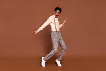 Fototapeta na wymiar Full length body size view of attractive cheerful carefree guy dancing having fun good mood isolated over brown color background