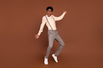 Photo of funky positive guy dance crazy moves wear suspenders sneakers isolated brown color background