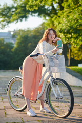 Fototapeta na wymiar A dark-haired young girl with a bike making selfie in the park