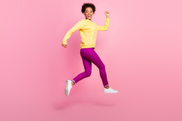 Photo of attractive beautiful lady wear yellow pullover running fast jumping high smiling isolated pink color background