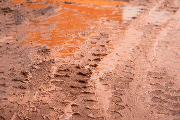 Dirt terrain road with wheel track on wet muddy surface. Transportation and road way, background and texture photo. Selective focus at the center part.