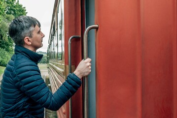 Close-up of a man holding on to a handrail as he walks on a train