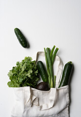 green vegetables in reusable bag on white background