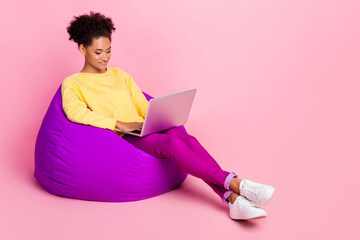 Photo of adorable pretty lady wear yellow pullover sitting bean bag typing modern device empty...