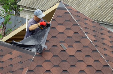 The roofer on the roof does the preparatory work for laying the slate