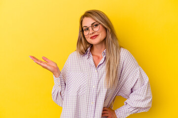 Young russian woman isolated on yellow background doubting and shrugging shoulders in questioning gesture.