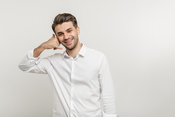 Smiling young unshaven business man in light shirt posing isolated on white wall background....