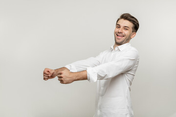 Portrait of nice attractive confident cheerful cheery glad bearded guy wearing classic white shirt holding in hands driving invisible car isolated over white background