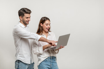 Portrait of charming inspired couple using laptop watching videos browsing sites social networks...