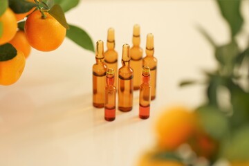 Vitamin C. Mesotherapy serum with vitamin C.Glass ampoules and tangerine fruit bushes on beige...