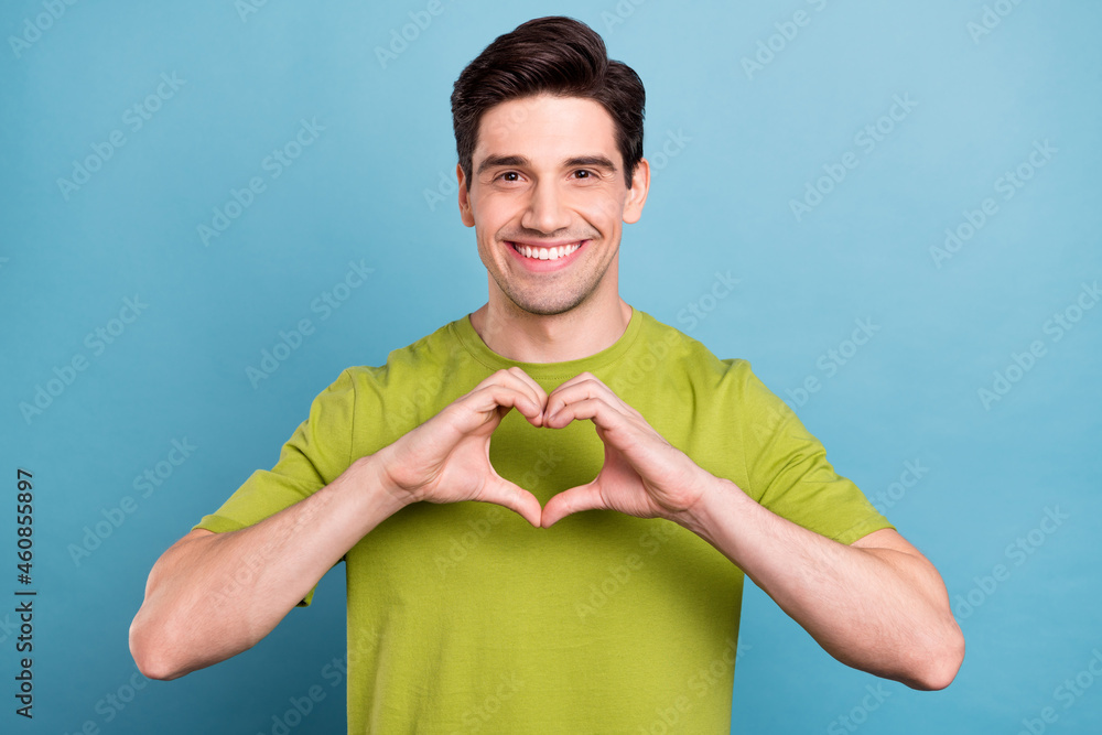 Sticker Portrait of attractive cheerful healthy guy showing heart sign cupid amour isolated over bright blue color background