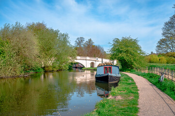 View of the river Gade (part of Grand Union Canal) and The Grove Bridge (Grove Ornamental Bridge No 164) in Cassiobury Park, England. Moored narrow boat, reflection on water. © Apostolis Giontzis