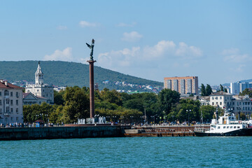 Column "Sea Glory of Russia" with fountain on embankment of Admiral Serebryakov. Angel with wings stands on Column. In background is panorama of city with. Novorossiysk, Russia - September 15, 2021