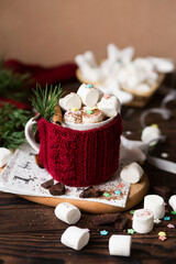 Obraz na płótnie Canvas Christmas hot chocolate with marshmallows. New Year's decor of the drink. Hot chocolate with cinnamon. Cocoa with milk in a knitted mug. Christmas drink for children.