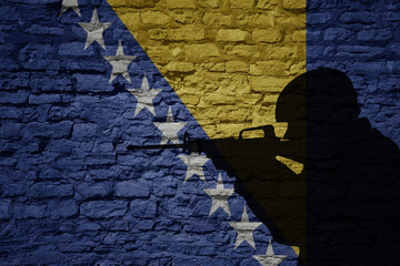 Soldier silhouette on the old brick wall with flag of bosnia and herzegovina country.