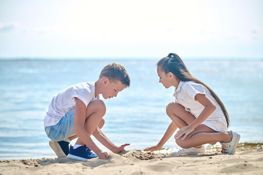 Two Kids Making Sand Castles And Looking Involved