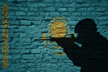Soldier silhouette on the old brick wall with flag of kazakhstan country.