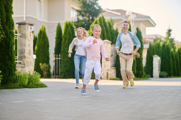 Cheerful running little girl and catching up parents