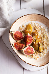 Close up of bowl with oatmeal porridge with figs and bananas for breakfast