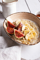 Breakfast with oatmeal porridge decorated with figs and bananas