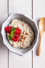 Bowl with cereal porridge decorated with raspberries and mint