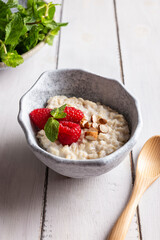 Bowl with cereal porridge decorated with raspberries and mint