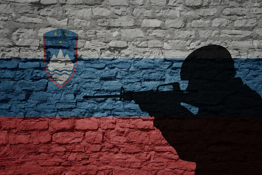 Soldier silhouette on the old brick wall with flag of slovenia country.