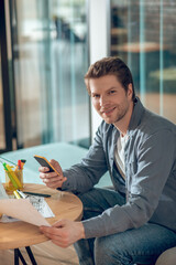 Friendly man with scheme sitting with smartphone