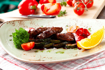 Fried meat and zucchini on a plate. On a wooden table.