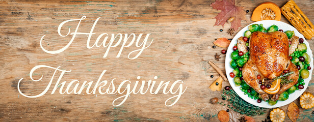 Happy Thanksgiving lettering on a festive dinner background. Food table background with autumn seasonal specialties for Thanksgiving Day. Fried chicken with pumpkin, vegetables and autumn decor