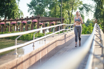 Fototapeta na wymiar A woman in grey sportswear jogging in the park