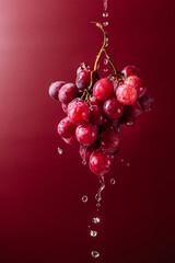 Pink grapes on pink background with splashing water