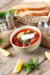 Traditional hodgepodge soup in a plate. On a wooden table.