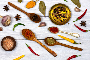 Spices, hot peppers, spoons with spices on a white wooden background