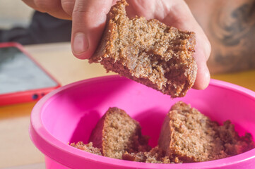 chocolate cake with cinnamon in a pink bowl with copy space and hand holding
