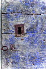 Metal lock in an old wooden door, colored blue.