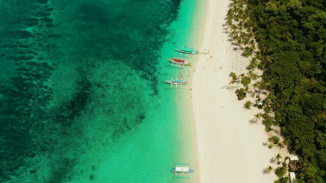 Tropical white sand beach, near the blue lagoon and corall reef from above, Boracay, Philippines. Sandy beach with tourists. Summer and travel vacation concept.
