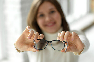 Woman with poor eyesight. A beautiful girl wears glasses to improve her vision. High quality photo