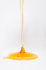 trickle of fresh golden honey flowing on white
