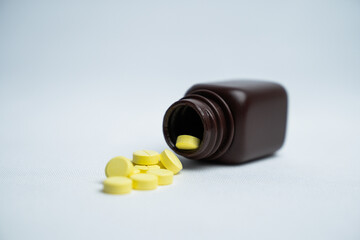 Brown pill bottle spilling pills on a white background