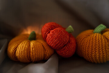 three knitted pumpkins from woolen yarn on a dark gray background. free space for an inscription. handmade. do it yourself. preparation for halloween.
