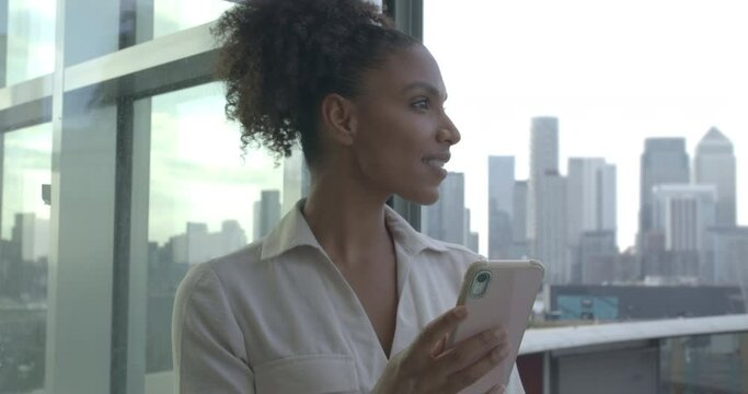 African American businesswoman using smartphone with view of city skyline in background