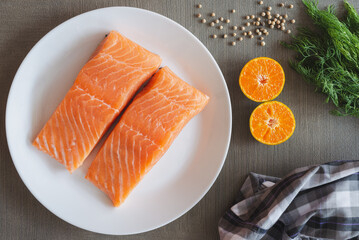 Fillets of salmon in white plate side with orange, black pepper and dill. Salmon is delicious and healthy fish. Salmon is famous in the world it can use in western food and eastern food.