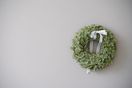 Christmas decorative wreath with a gray bow on the background of a gray concrete wall with a copy space