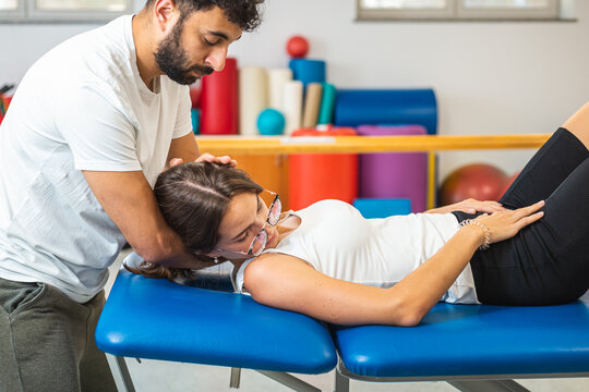 Close-up shot of a male physiotherapist doing manual neck stretching to a young Caucasian female patient.