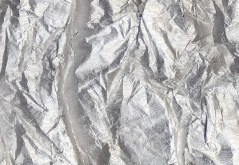 Grunge overlay. Crushed foil texture. Rough crumpled effect. Silver shimmering wrinkled uneven distressed metallic film surface with scratches abstract background.